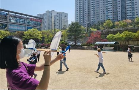 6학년 학생들이 고무동력기를 날리고 있다.