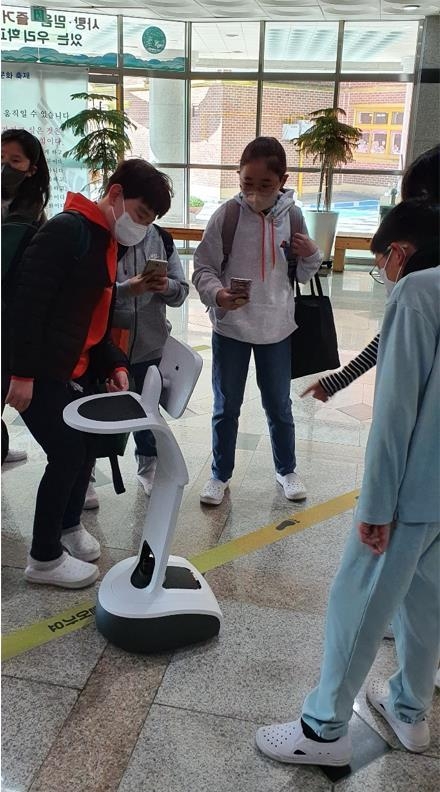 학생들이 AI 멀티로봇과 인사를 하고 있다.